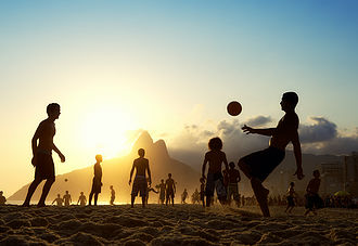 People kicking ball on beach